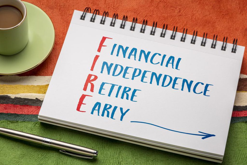 Financial Independence Retire Early escrito num caderno em cima de uma mesa com uma toalha, uma chávena de café e uma caneta.