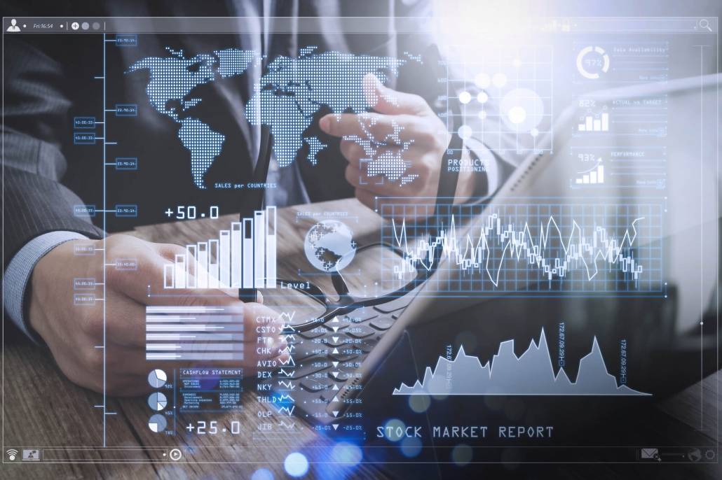 Homem de fato sentado numa mesa com uns óculos na mão e gráficos com transparência em primeiro plano.
