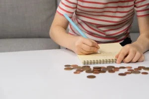 Jovem a escrever num caderno e a contar moedas